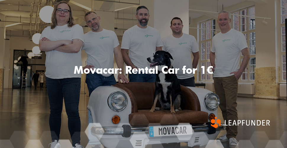 A team of people wearing white shirts, posing for a photo next to a dog sitting on a car-shaped sofa
